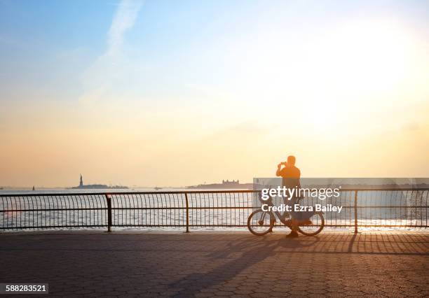 man taking a photo on his phone at sunset. - photographing sunset stock pictures, royalty-free photos & images