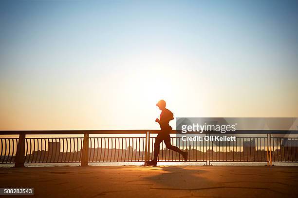 man enjoying an early morning jog in the city. - jogging city stock-fotos und bilder