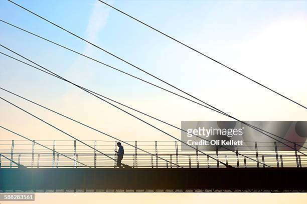 businessman walking to work at sunrise in the city - cable stayed bridge stock-fotos und bilder