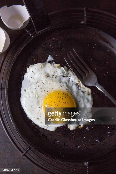 fried sunny side up egg in frying pan with fork, high angle view - stekt ägg bildbanksfoton och bilder