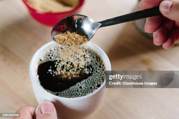 brown sugar being poured into cup of coffee, high angle view - sugar spoon stock pictures, royalty-free photos & images