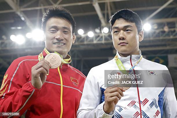 Bronze medallists China's Cheng Xunzhao and South Korea's Gwak Donghan celebrate on the podium of the men's -90kg judo contest of the Rio 2016...