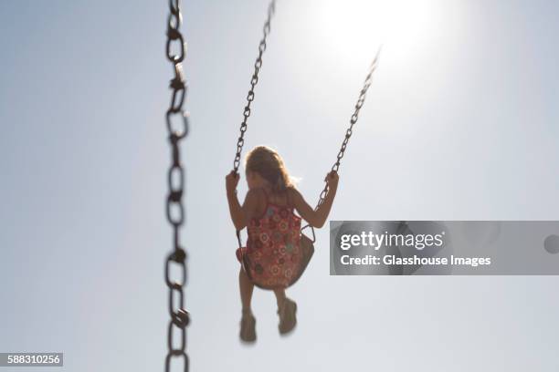 young girl playing on swing, rear view - selective focus imagens e fotografias de stock