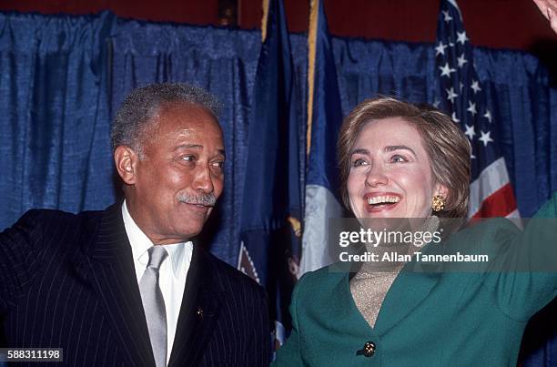 As New York City Mayor David Dinkins watches American lawyer ( First Lady Hillary Rodham Clinton waves fron the stage during a Dinkins' reelection...