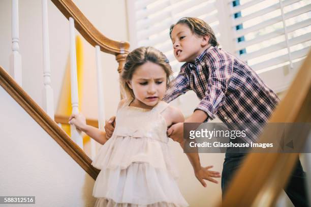 boy grabbing girl's arm on stairs - annoying brother stock pictures, royalty-free photos & images