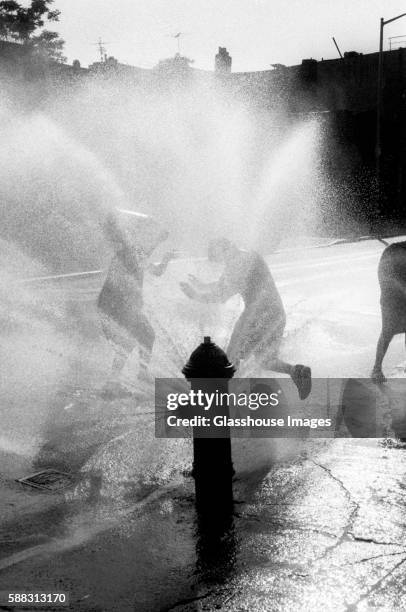 children playing by water spraying hydrant - fire hydrant stock pictures, royalty-free photos & images