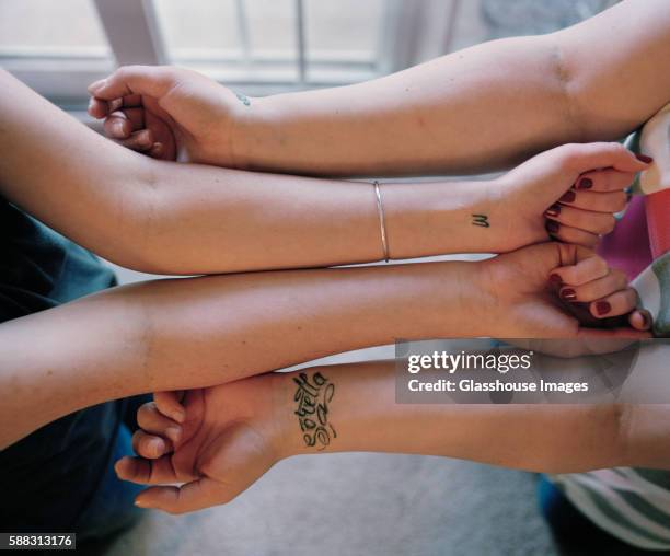 two young women's bare arms with wrist tattoos next to each other, palms up, high angle view - wrist stock pictures, royalty-free photos & images