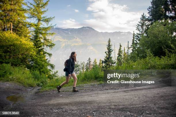 young adult woman hiking on mountain trail at sunrise with alps in background, col du mont cenis, val cenis vanoise, france - parque nacional vanoise fotografías e imágenes de stock