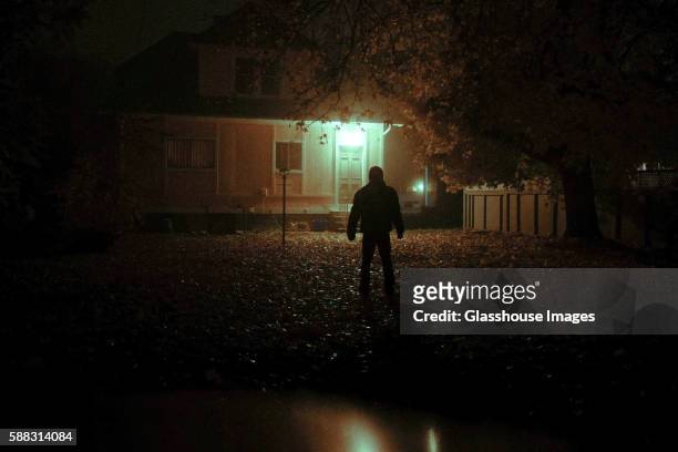 mysterious man looking at house from backyard at night - a haunted house stockfoto's en -beelden