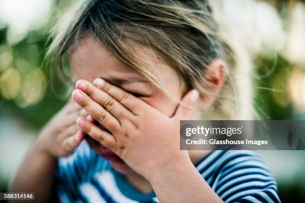 young girl crying with hands covering face - huilen stockfoto's en -beelden