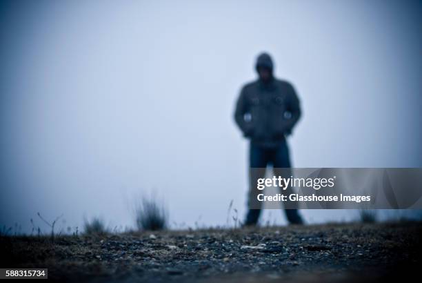 blurred hooded figure in fog - molestatore foto e immagini stock