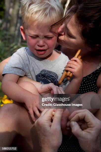 crying boy having splinter removed from foot while being held by mother - sliver stock pictures, royalty-free photos & images