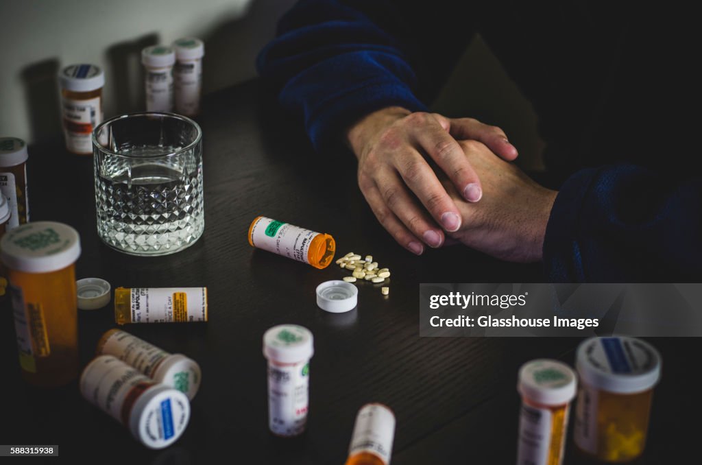 Hands of Man in Robe Surrounded by Prescription Pill Bottles