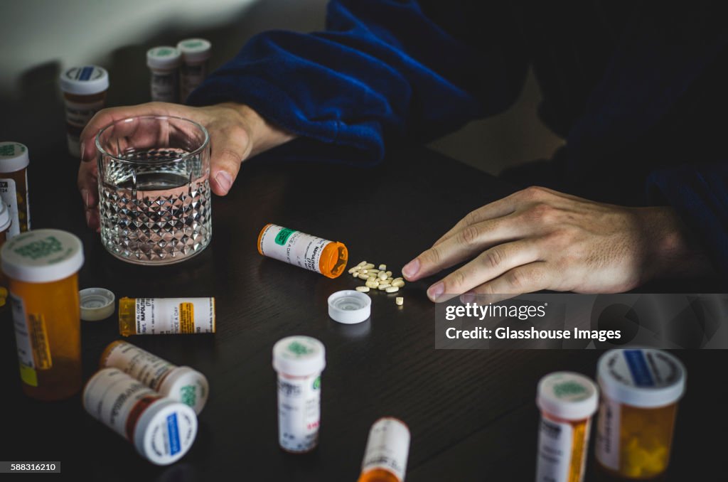Hands of Man in Robe Surrounded by Prescription Pill Bottles