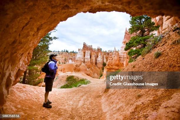 man hiking through arch, bryce canyon national park, utah, usa - 33 arches stock pictures, royalty-free photos & images