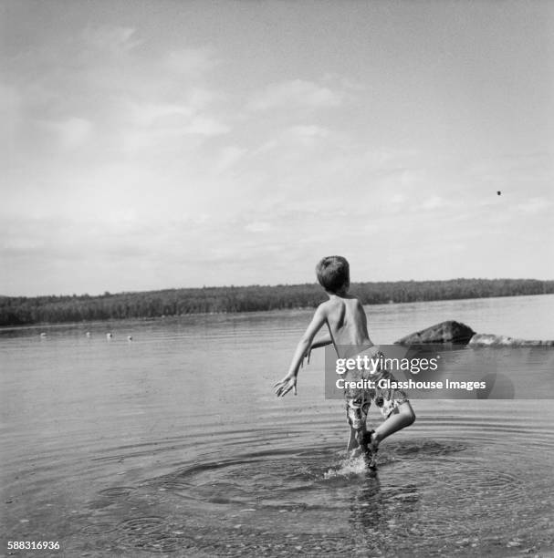young boy throwing rock in lake - badkläder bildbanksfoton och bilder