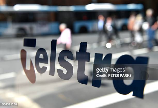 People pass a Telstra phone booth on a street in Sydney on August 11, 2016. Australia's dominant telecommunications company Telstra reported a 36.6...