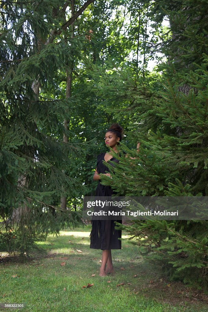 Young woman in green evergreen trees