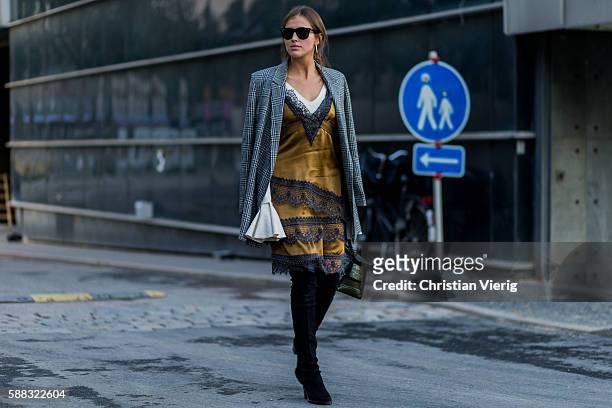Darja Barannik wearing a grey plaid coat, golden dress and overknee boots outside Lala Berlin during the first day of the Copenhagen Fashion Week...