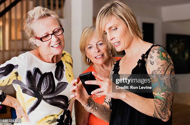 tattooed woman showing women details on smartphone - old woman tattoos stock pictures, royalty-free photos & images