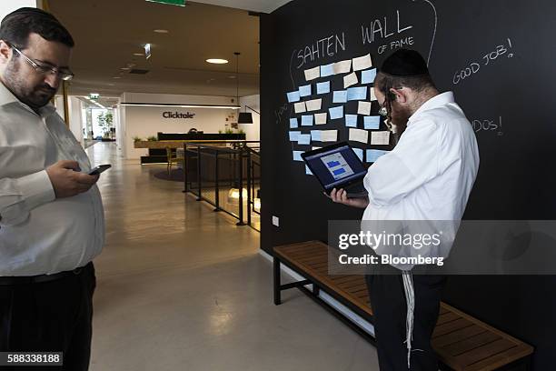 Moshe Friedman, co-founder and chief executive officer of KamaTech, checks his smartphone while an ultra Orthodox tech entrepreneur works on a laptop...