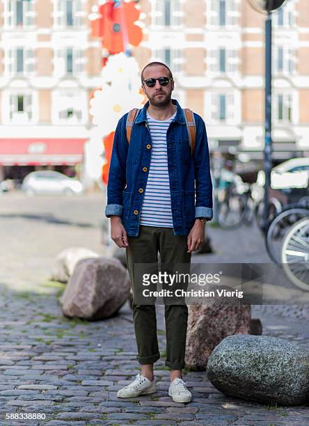 Chris Scholes wearing sunglasses, a backpack, a denim shirt, a striped tshirt, an olive pants and white court sneakers outside Revolver Fair during...