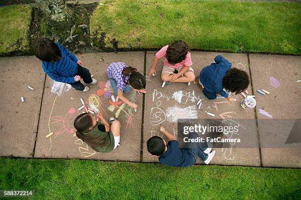 gruppo di bambini piccoli che disegnano con il gesso sul marciapiede - gessetto da lavagna foto e immagini stock