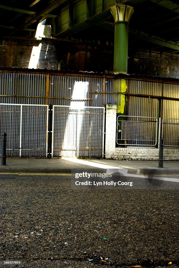 Road under railway bridge lit by sunlight