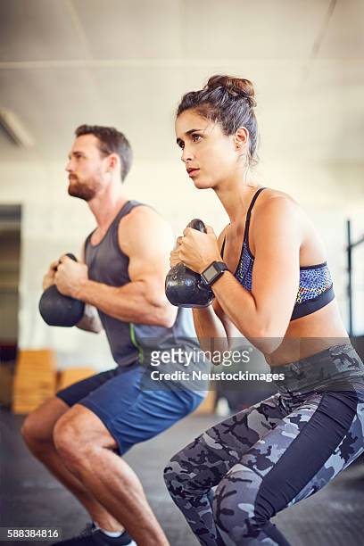 junge frau mit lehrer heben kesselglocken in fitness-studio - weight lifting stock-fotos und bilder