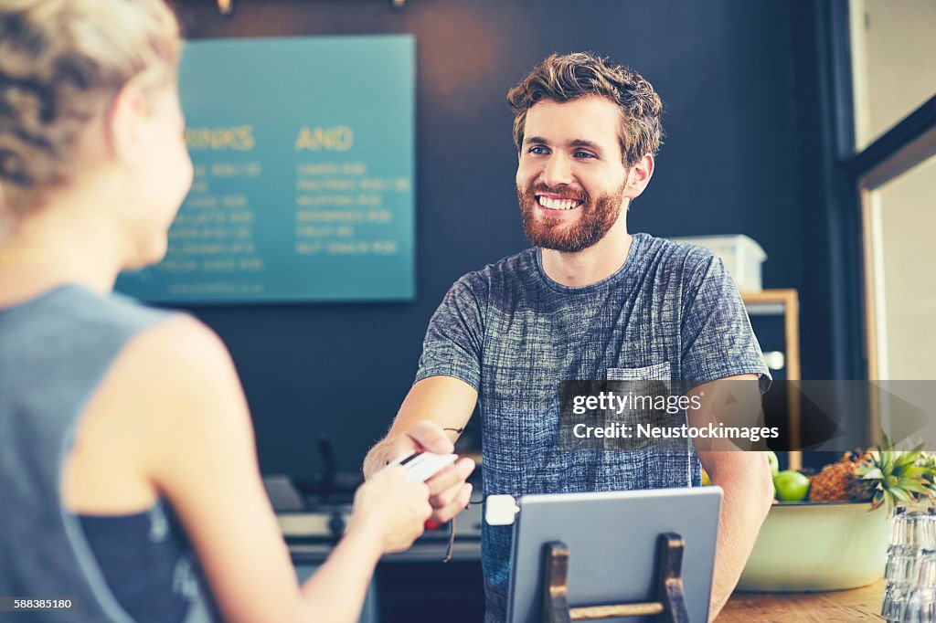 Cashier looking at customer while receiving card