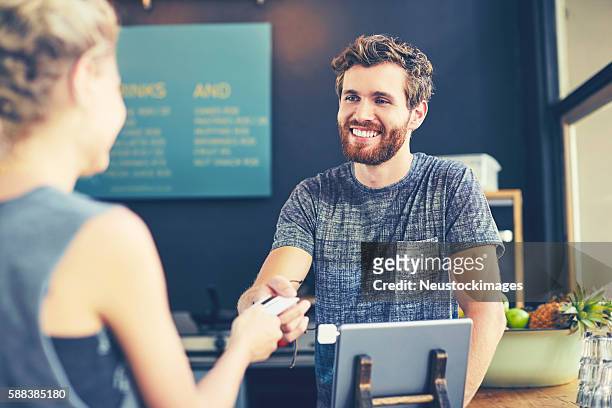 cashier looking at customer while receiving card - debit cards credit cards accepted stock pictures, royalty-free photos & images