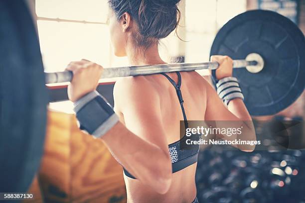 vue arrière de la femme faisant de l’exercice avec l’haltère dans la salle de gym - entraînement musculaire photos et images de collection