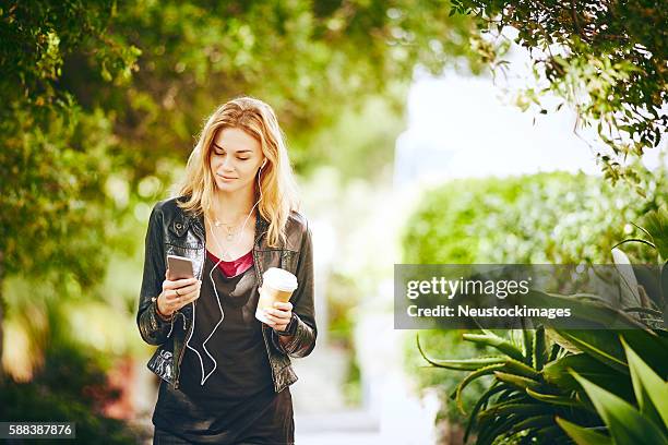 beautiful young woman listening music while holding disposable c - disposable cup stock pictures, royalty-free photos & images