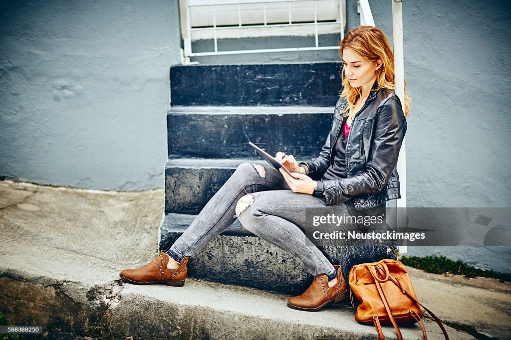 Full length of beautiful woman using digital tablet on steps