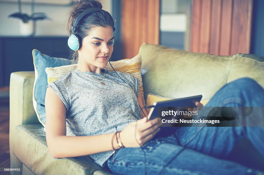 Young woman listening to music on tablet computer at home