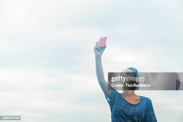 woman holding smart phone in the air. - photographing bildbanksfoton och bilder