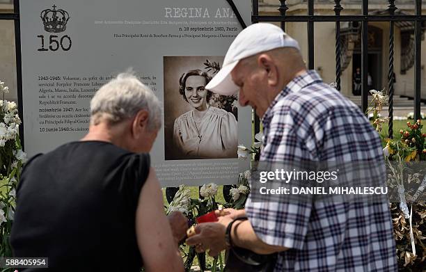 People light candle next to the portrait of the late Queen Anne of Romania at the Royal Palace, now The Art Museum of Romania, in Bucharest August...