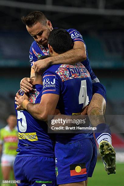 Sam Perrett of the Bulldogs celebrates with Curtis Rona and Josh Reynolds after scoring a try during the round 23 NRL match between the Canterbury...