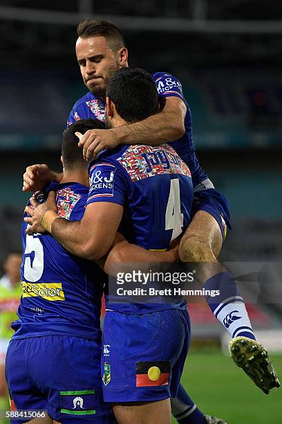 Sam Perrett of the Bulldogs celebrates with Curtis Rona and Josh Reynolds after scoring a try during the round 23 NRL match between the Canterbury...