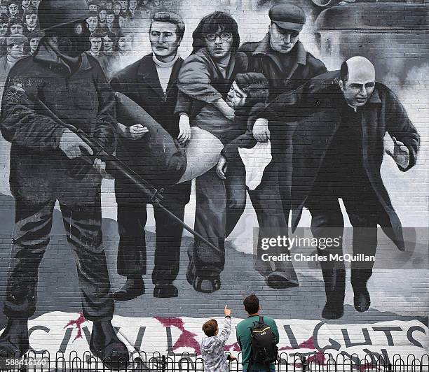 Young boy points at a mural depicting a scene from Bloody Sunday as final preparations for the funeral of the late retired Bishop of Derry, Dr....