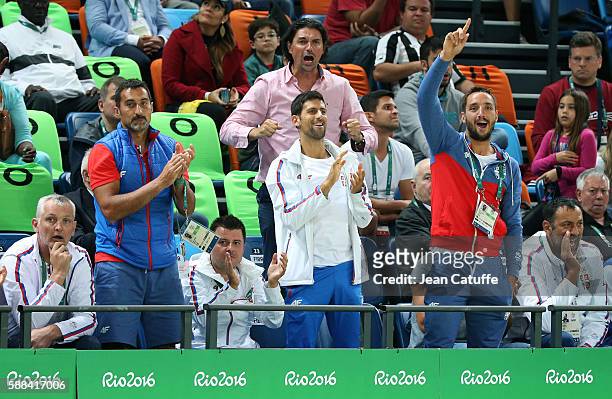The Serbian tennis team Nenad Zimonjic, Novak Djokovic and Viktor Troicki cheer for Team Serbia during the men's basketball match between France and...
