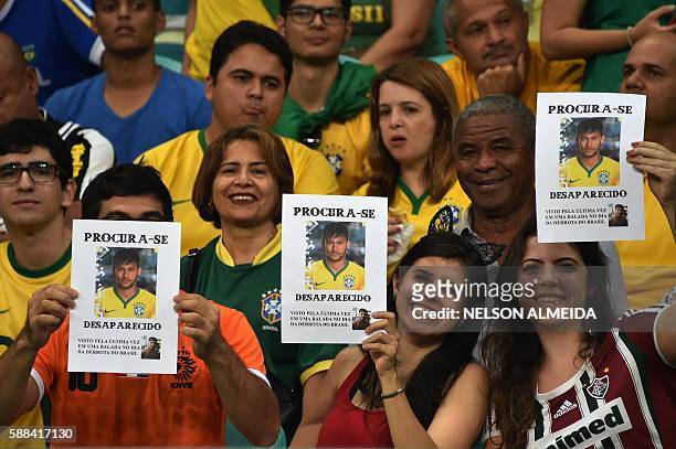 Brazil's supporters hold photos of Brazilian footballer Neymar reading "Wanted. Disappeared" as they cheer for their team during the Rio 2016 Olympic...