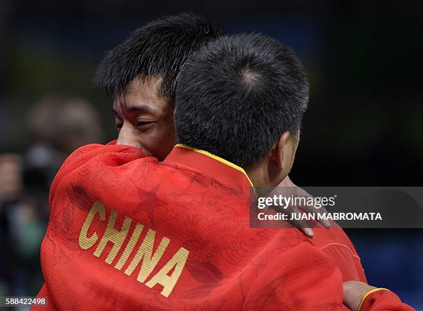 China's Zhang Jike hugs his coach after beating Belarus' Vladimir Samsonov in their men's singles semi-final table tennis match at the Riocentro...