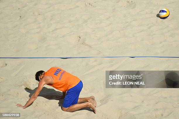 Reinder Nummerdor of the Netherlands kneels on the court during the men's beach volleyball qualifying match with his teammate Christiaan Varenhorst...