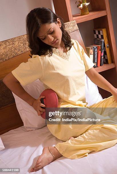 woman applying a hot water bag - hot hips 個照片及圖片檔