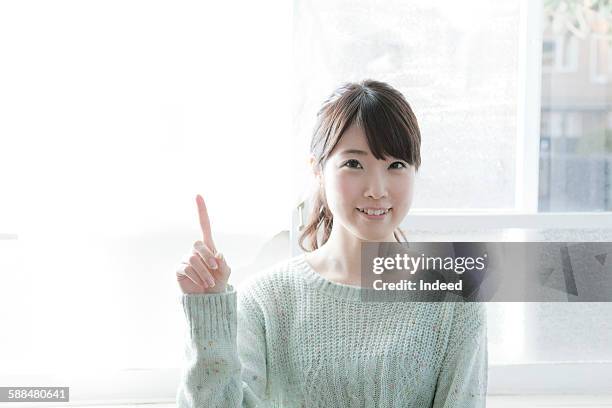 young woman pointing finger up - woman index finger stock pictures, royalty-free photos & images