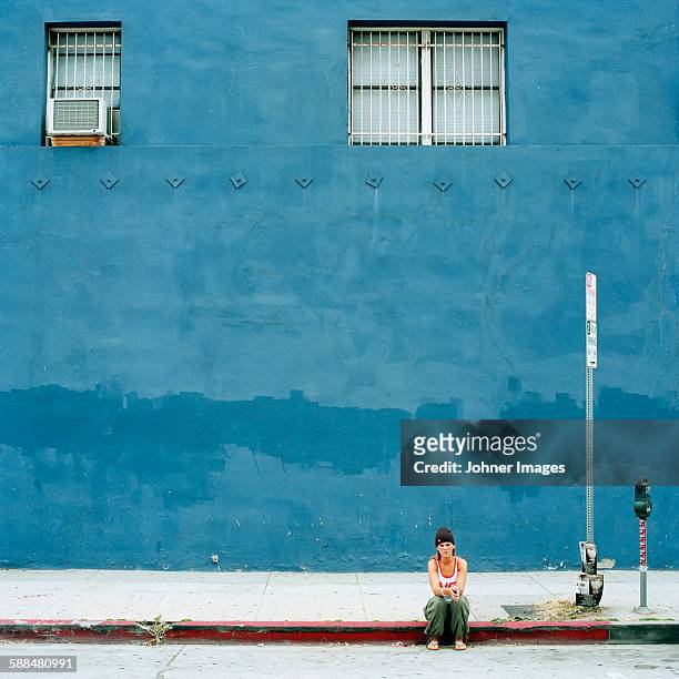 woman sitting in front of blue building - hollywood california stock-fotos und bilder