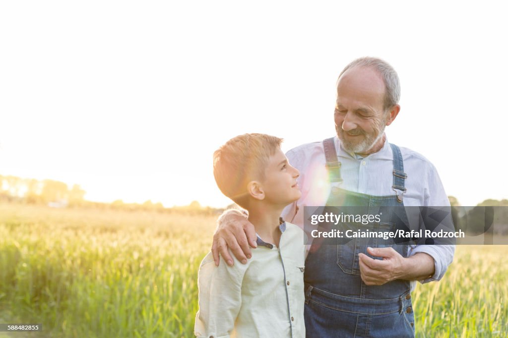 Nonno contadino e nipote che si abbracciano nel campo di grano rurale