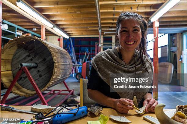 an artist carving jewellery from musk ox horns in her studio. - inuit foto e immagini stock