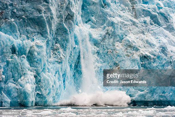 ice calving from the fracture zone of a glacier crashing into the ocean. - glacier calving stock pictures, royalty-free photos & images